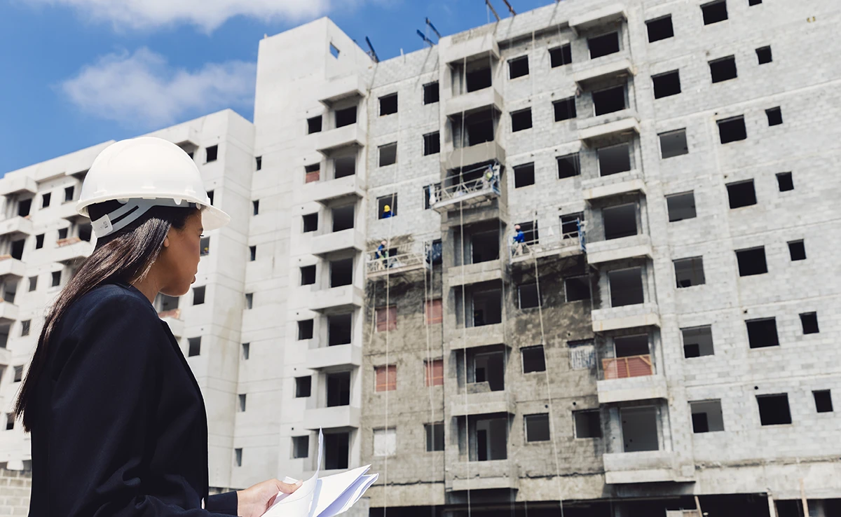 african-american-lady-safety-helmet-with-papers-near-building-construction